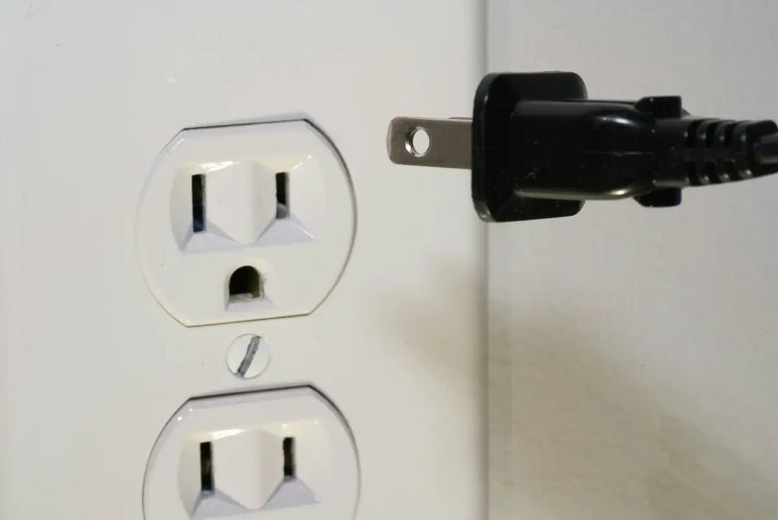 Un contacto eléctrico tipo B y un cable polarizado sin tierra a punto de conectarlo