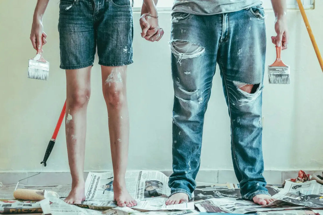 Dos personas manchadas por pintar pintura de color blanco sobre un periodico
