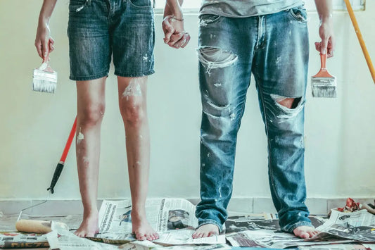 Dos personas manchadas por pintar pintura de color blanco sobre un periodico